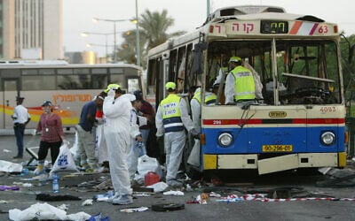 Israeli police officers and Zaka rescue and recovery volunteers work inside and next to a destroyed bus at the scene of a double bombing in the southern Israeli city of Beersheba, August. 31, 2004. (AP Photo/Brennan Linsley)