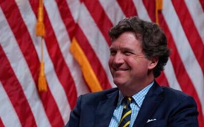 Tucker Carlson listens as then Republican US presidential nominee Donald Trump speaks during a Tucker Carlson Live Tour show in Glendale, Arizona, October 31, 2024. (AP Photo/Julia Demaree Nikhinson)
