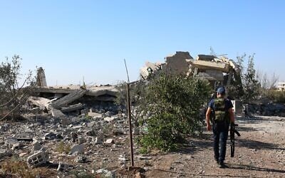 A gunman walks by the remains of a house destroyed during the recent sectarian clashes in the Druze-majority town of Sweida, southern Syria, on September 19, 2025. (AP Photo/Fahd Kiwan)