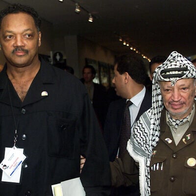 Civil rights activist Jesse Jackson, left, walks with Palestinian leader Yasser Arafat after the opening ceremony of the World Conference Against Racism in Durban, South Africa, August 31, 2001. (AP Photo/Jose Goitia, File)