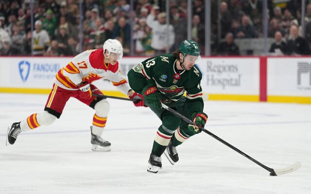 Minnesota Wild defenseman Quinn Hughes (43) skates with the puck as Calgary Flames center Yegor Sharangovich (17) follows during the third period of an NHL hockey game, Jan. 29, 2026, in St. Paul, Minnesota. (AP/Abbie Parr) Minnesota Wild defenseman Quinn Hughes (43) skates with the puck as Calgary Flames center Yegor Sharangovich (17) follows during the third period of an NHL hockey game, Jan. 29, 2026, in St. Paul, Minnesota. (AP/Abbie Parr)