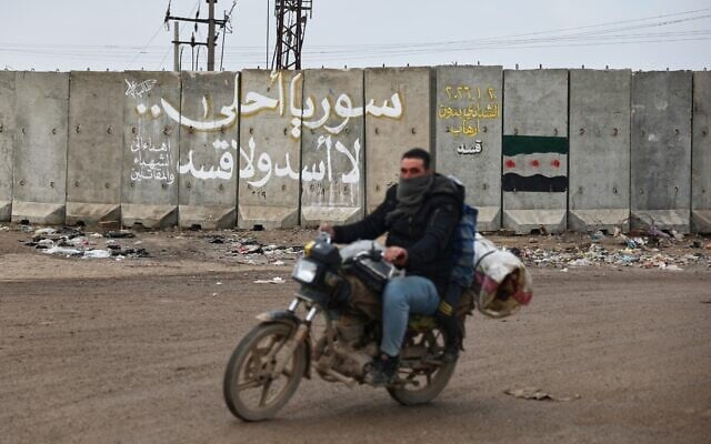 A man rides his motorcycle past the wall of a US military base bearing graffiti in Arabic that reads, 'Syria is more beautiful, no Assad, no SDF,' and in yellow, 'Al-Shaddadi without SDF terrorism,' near the village of Al-Shaddadi, al-Hassakeh province, eastern Syria, Feb. 2, 2026. (AP Photo/Ghaith Alsayed) A man rides his motorcycle past the wall of a US military base bearing graffiti in Arabic that reads, 'Syria is more beautiful, no Assad, no SDF,' and in yellow, 'Al-Shaddadi without SDF terrorism,' near the village of Al-Shaddadi, al-Hassakeh province, eastern Syria, Feb. 2, 2026. (AP Photo/Ghaith Alsayed)