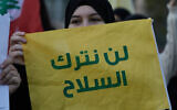A Hezbollah supporter holds a flag with a message that reads in Arabic: "We will not lay down the weapons" during a protest in Beirut, Lebanon, February 4, 2026. (AP Photo/Bilal Hussein)