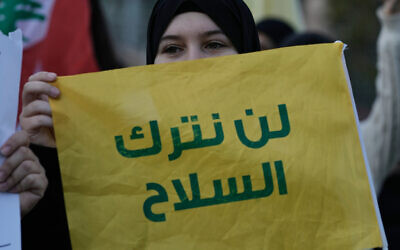 A Hezbollah supporter holds a flag with a message that reads in Arabic: "We will not lay down the weapons" during a protest in Beirut, Lebanon, February 4, 2026. (AP Photo/Bilal Hussein) A Hezbollah supporter holds a flag with a message that reads in Arabic: "We will not lay down the weapons" during a protest in Beirut, Lebanon, February 4, 2026. (AP Photo/Bilal Hussein)