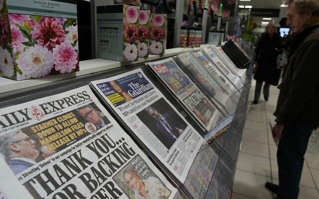 A man looks at newspapers on sale showing headlines relating to the Epstein files in London, on February 5, 2026. (AP Photo/Kin Cheung)