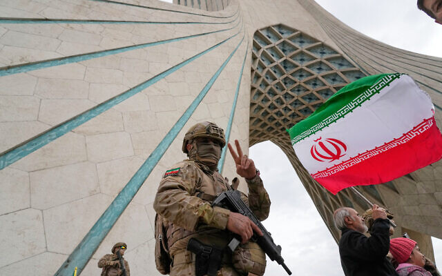 A member of the Revolutionary Guard flashes a victory sign while taking position as a man holds an Iranian flag under the Azadi, or freedom, monument tower during an annual rally marking 1979 Islamic Revolution at the Azadi square in Tehran, Iran, Wednesday, Feb. 11, 2026. (AP Photo/Vahid Salemi) A member of the Revolutionary Guard flashes a victory sign while taking position as a man holds an Iranian flag under the Azadi, or freedom, monument tower during an annual rally marking 1979 Islamic Revolution at the Azadi square in Tehran, Iran, Wednesday, Feb. 11, 2026. (AP Photo/Vahid Salemi)