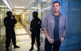 Russian opposition leader Alexei Navalny speaks to the media in front of security officers standing guard at the Foundation for Fighting Corruption office in Moscow, Russia, Dec. 26, 2019. (AP Photo/Alexander Zemlianichenko, File)