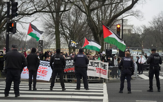 People hold Palestinian flags as they protest outside of the U.S. Institute of Peace, Thursday, Feb. 19, 2026, in Washington. (AP Photo/Mark Schiefelbein)