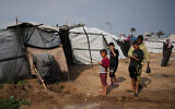 Palestinian Lubna Abu Sirya digs a small channel to drain rainwater that flooded her tent in Deir al-Balah, central Gaza Strip, February 24, 2026. (AP/Abdel Kareem Hana)