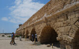 Israelis and tourists enjoy the beach where a 2,000-year-old arch of the Caesarea aqueduct collapse, as seen on August 21, 2023.  (Michael Giladi/Flash90)