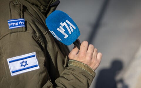 An IDF soldier serving at Army Radio holds a microphone in Jerusalem, December 22, 2025. (Yonatan Sindel/Flash90)