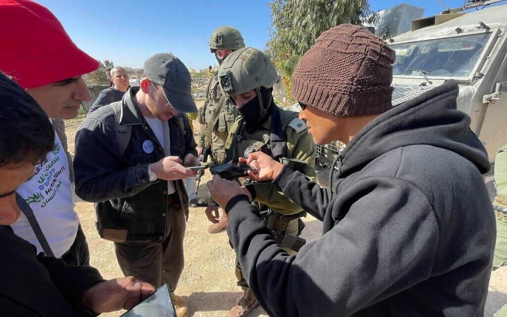Residents of Umm al-Khair and coexistence activists remonstrate with an IDF officer after the army thwarted a tree-planting event in the Palestinian hamlet of Umm al-Khair in the West Bank, February 2, 2026 (Jeremy Sharon/Times of Israel)
