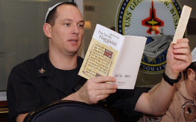 Information Systems Technician 1st Class Christopher Smith recites Passover liturgy during a seder aboard the aircraft carrier USS George H.W. Bush (CVN 77). George H.W. Bush is supporting maritime security operations and theater security cooperation efforts in the U.S. 5th Fleet area of responsibility. (U.S. Navy photo by Mass Communication Specialist 3rd Class Maggie Keith/Released)