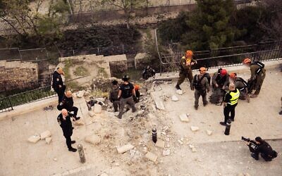 Israeli security personnel at the scene where a fragment from an intercepted Iranian ballistic missile impacted in the Jewish Quarter of Jerusalem's Old City on March 20, 2026, damaging a road and a wall. (IDF Spokesman)