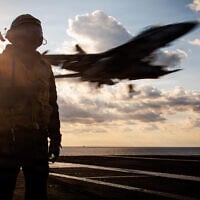 A US service member stands by as an F/A-18F Super Hornet aircraft lands on the flight deck aircraft carrier USS Gerald R. Ford while operating in support of Operation Epic Fury in the Eastern Mediterranean Sea, March 2, 2026. (US Navy)