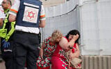 Illustrative: Rescue teams help shocked residents in a targeted residential neighborhood in the southern city of Ashkelon on May 11, 2021, after rockets were fired by Hamas from the Gaza Strip. (JACK GUEZ / AFP)