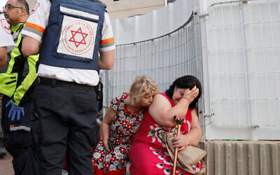 Illustrative: Rescue teams help shocked residents in a targeted residential neighborhood in the southern city of Ashkelon on May 11, 2021, after rockets were fired by Hamas from the Gaza Strip. (JACK GUEZ / AFP)