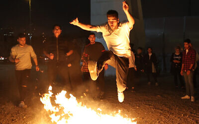 Illustrative: An Iranian jumps over a bonfire during the pre-Islamic Persian fire festival of Chaharshanbe Suri, held annually on the last Wednesday eve before the Spring holiday of Nowruz, in Tehran, Iran, on March 14, 2023. (ATTA KENARE / AFP)
