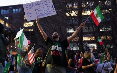 A man holds up an Iranian pre-1979 Islamic Revolution flag and a sign reading "Khamenei is dead!" during a rally expressing support for US and Israeli military action against Iran's Islamic Republic regime on February 28, 2026 in Atlanta, Georgia. (Elijah Nouvelage / AFP)