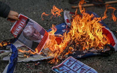 A protester sets fire to an image depicting a mugshot of US President Donald Trump and reading "Wanted Donald Trump is wanted by all Shia Muslims in the world" during a protest against the US-Israel attack of Iran and the killing of the supreme leader, in front of Israeli Consulate in Istanbul, on March 1, 2026. (Ozan KOSE / AFP)
