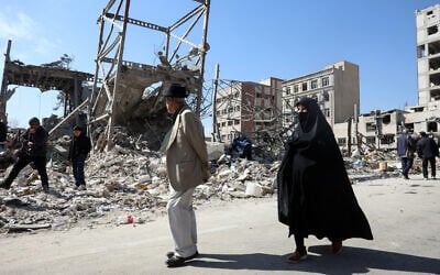 A man and a woman walk past destroyed buildings following airstrikes in central Tehran, on March 4, 2026. (AFP)