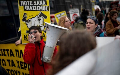 A protester shouts slogans in a megaphone during an antifascist demonstration outside of the Greek court of appeal during the trial of far-right party Golden Dawn, March 4, 2026. (Aggelos NAKKAS / AFP)