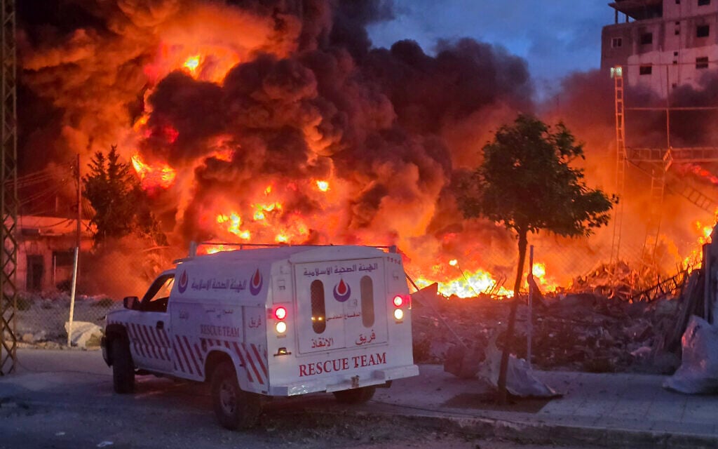 An ambulance is parked near a sweeping blaze following an Israeli strike on a solar farm and electricity generation facility in Lebanon's southern coastal city of Tyre on March 4, 2026. (Kawnat HAJU / AFP)