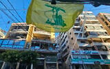 A Hezbollah flag flutters outside damaged buildings following Israeli airstrikes in Beirut's southern suburbs of Ghobeiry neighborhood, on March 5, 2026. (AFP)