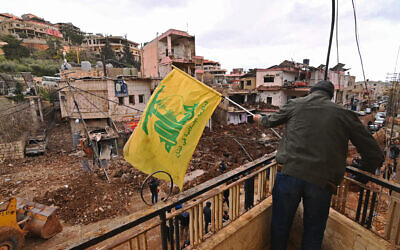 This photograph taken during a media tour organized by Hezbollah shows a man installing a flag of Hezbollah on the balcony of a damaged building at Nabi Chit town after an Israeli military operation in the Bekaa Valley of Lebanon, on March 7, 2026. (Photo by FADEL itani / AFP) This photograph taken during a media tour organized by Hezbollah shows a man installing a flag of Hezbollah on the balcony of a damaged building at Nabi Chit town after an Israeli military operation in the Bekaa Valley of Lebanon, on March 7, 2026. (Photo by FADEL itani / AFP)