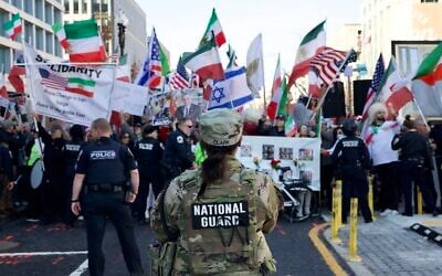 Police and members of the National Guard stand in front of demonstrators from the Iranian diaspora waving pre-Islamic revolution Iranian, Israeli and US flags as they protest against the Iranian government in front of the White House in Washington, DC, on March 7, 2026. (Amid FARAHI / AFP)