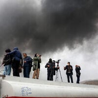 Journalists stand atop a fuel tanker as they cover a nearby ongoing fire following an overnight airstrike on the Shahran oil refinery in northwestern Tehran on March 8, 2026. (AFP)
