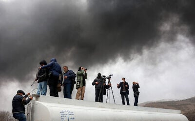 Journalists stand atop a fuel tanker as they cover a nearby ongoing fire following an overnight airstrike on the Shahran oil refinery in northwestern Tehran on March 8, 2026. (AFP)