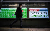 A man walks past an electronic quotation board displaying numbers of the Nikkei Stock Average on the Tokyo Stock Exchange along a street in Tokyo on March 9, 2026. (Philip FONG / AFP)