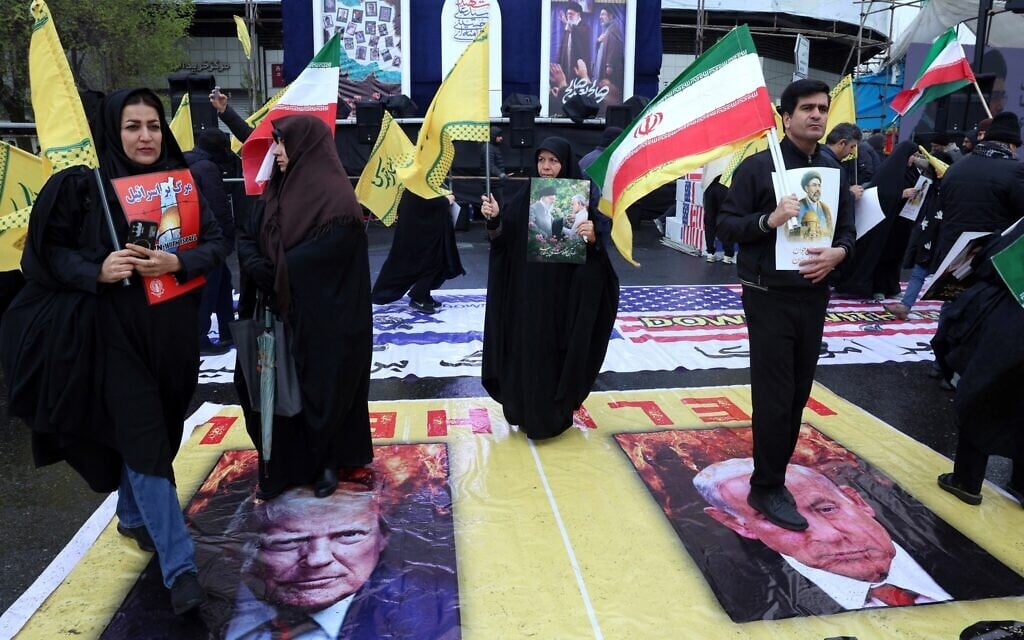 Iranians stand on posters depicting images of the US president Donald Trump and Israeli Prime Minister Benjamin Netanyahu as they take part in the Quds Day rally in Tehran on March 13, 2026. (AFP)
