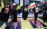 Iranians stand on posters depicting images of the US president Donald Trump and Israeli Prime Minister Benjamin Netanyahu as they take part in the Quds Day rally in Tehran on March 13, 2026. (AFP)