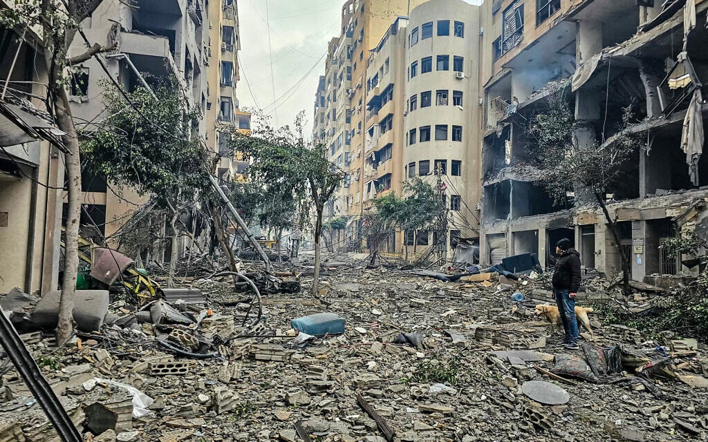 A man and his dog walk across the rubble of a building at the site of an Israeli airstrike in Beirut's southern suburb Haret Hreik on March 15, 2026. (AFP) A man and his dog walk across the rubble of a building at the site of an Israeli airstrike in Beirut's southern suburb Haret Hreik on March 15, 2026. (AFP)