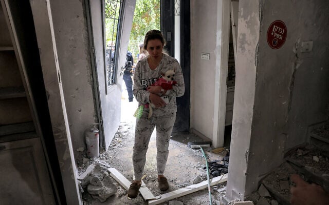 A woman carrying a dog stands in a building damaged in an Iranian missile attack in Rishon Lezion in central Israel on March 16, 2026 (AHMAD GHARABLI / AFP) A woman carrying a dog stands in a building damaged in an Iranian missile attack in Rishon Lezion in central Israel on March 16, 2026 (AHMAD GHARABLI / AFP)