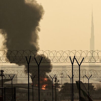 The Dubai skyline with the landmark Burj Khalifa skyscraper (R) is pictured as a smoke plume rises from an ongoing fire near Dubai International Airport, United Arab Emirates, on March 16, 2026. (AFP)
