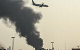 A FlyDubai aircraft prepares to land as a smoke plume rises from an active fire near Dubai International Airport in Dubai on March 16, 2026. (AFP)