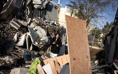 A woman walks through the site of a March 21, 2026, Iranian missile strike in the city of Dimona on March 22, 2026. (JOHN WESSELS / AFP) /