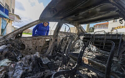 A Palestinian boy looks at a burnt vehicle following an attack by extremist settlers in the village of Jalud, south of Nablus in the West Bank, on March 22, 2026. (JAAFAR ASHTIYEH / AFP)