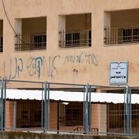 Graffiti daubed by Jewish settlers that reads, "A good Arab is a dead Arab" stains the walls of the Palestinian Huwara Secondary School, where an Israeli flag reportedly placed on the school's roof by Israeli settlers was removed and the Palestinian flag restored by the school in Huwara, south of the city of Nablus in the West Bank on March 23, 2026.(Jaafar ASHTIYEH / AFP)