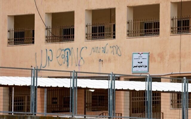Graffiti daubed by Jewish settlers that reads, "A good Arab is a dead Arab" stains the walls of the Palestinian Huwara Secondary School, where an Israeli flag reportedly placed on the school's roof by Israeli settlers was removed and the Palestinian flag restored by the school in Huwara, south of the city of Nablus in the West Bank on March 23, 2026.(Jaafar ASHTIYEH / AFP)