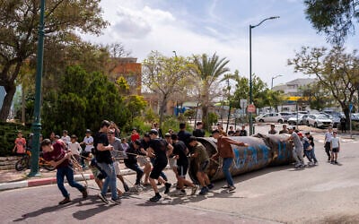 Children move a part of an Iranian missile remnant that fell in a school courtyard in the Israeli settlement of Peduel, West Bank on March 23, 2026. (Maya Levin / AFP) Children move a part of an Iranian missile remnant that fell in a school courtyard in the Israeli settlement of Peduel, West Bank on March 23, 2026. (Maya Levin / AFP)
