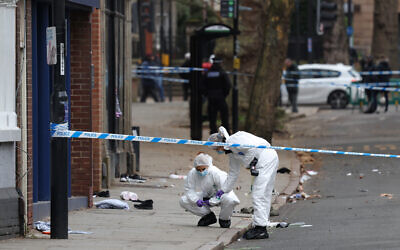 Police forensic officers work amongst a variety of personal items seen covering the road, inside a cordon set up on Friar Gate in central Derby, central England on March 29, 2026, after a man was arrested the previous night when a car hit pedestrians, wounding seven people. (Darren Staples / AFP)