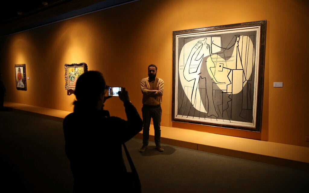Visitors pose alongside Pablo Picasso's "The painter and his model" while visiting an exhibition at the Museum of Contemporary Art in Tehran, Iran, March 9, 2017. (AP Photo/Vahid Salemi)