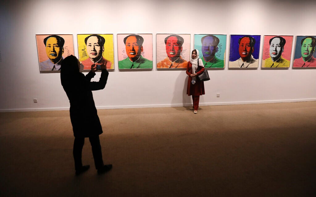 A visitor stands next to Andy Warhol's paintings of China's late leader, Mao Zedong, at Tehran Museum of Contemporary Art in Tehran, Iran on Oct. 19, 2021. (AP Photo/Vahid Salemi)