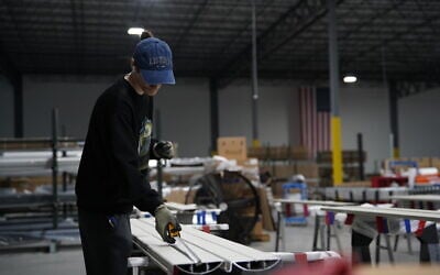 A worker takes measurements of an aluminum beam on the factory floor at The Luxury Pergola, a company that manufactures aluminum pergolas, on, February 20, 2026, in Noblesville, Indiana. (AP Photo/Obed Lamy)