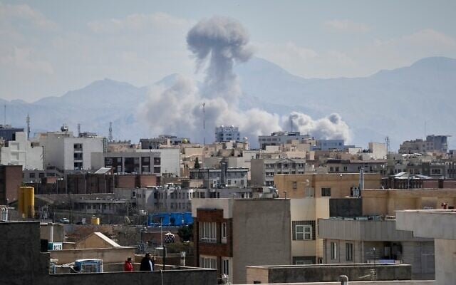 People watch from a rooftop as a plume of smoke rises after a strike in Tehran, Iran, March 1, 2026. (AP/Vahid Salemi)