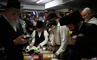 Jewish men and children, some dressed in costumes, read the Scroll of Esther as they celebrate the holiday of Purim in an underground parking garage as a precaution against Iranian missile attacks, in Tel Aviv, March 2, 2026. (AP Photo/Ohad Zwigenberg)